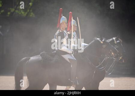 I membri della Household Cavalry si buttano in polvere mentre attraversano la Horse Guards Parade, Londra, mentre i britannici sono impostati per vivere la giornata più calda del Regno Unito, mentre si prevede che le temperature raggiungeranno il 40C. Data foto: Martedì 19 luglio 2022. Foto Stock