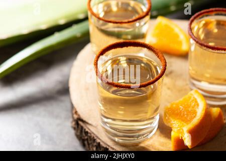 Mezcal bevanda messicana con fette d'arancia e sale di verme su tavola di legno Foto Stock