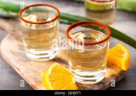 Mezcal bevanda messicana con fette d'arancia e sale di verme su tavola di legno Foto Stock