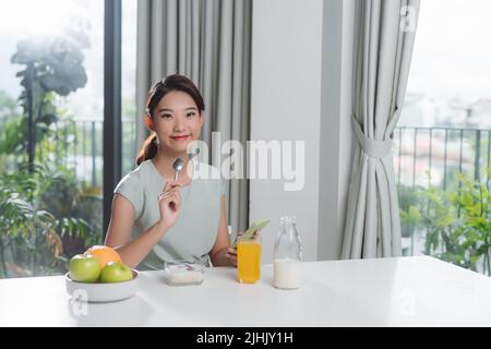 Ritratto di giovane e bella donna con la colazione in cucina. Foto Stock