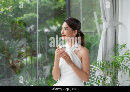 attraente giovane donna che beve acqua a casa Foto Stock