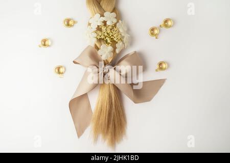 Un olio naturale essenziale o siero per la cura dei capelli in capsule dorate adagiate su un tavolo bianco. Cura dei capelli e concetto di lisciatura Foto Stock