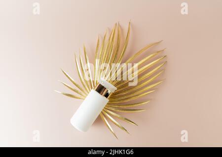 Una bottiglia bianca di tonico facciale adagiata su una foglia d'oro Foto Stock