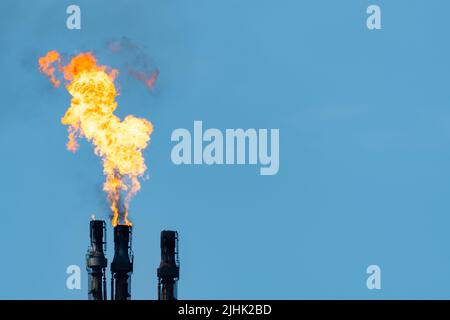 Gas di raffineria di petrolio, catasta di fiamma che brucia il gas in eccesso. Spazio copia a destra. Fiamma di raffineria di petrolio, fiocchi, flaring, camino, inquinamento, smokestack. REGNO UNITO Foto Stock