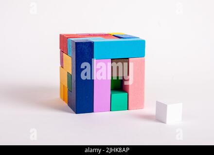 Cubo di legno da blocchi multicolore con un elemento mancante. Concetto dell'ultimo passo della costruzione. Giochi per bambini per lo sviluppo logico del pensiero. Foto di alta qualità Foto Stock