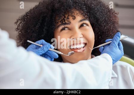 Sopra il colpo di una bella giovane donna afroamericana con un afro guardando il dentista al suo appuntamento dentale. Avere il suo controllo per prevenire Foto Stock