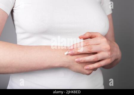 Donna che mette guarigione o dolore alleviare unguento al polso per ridurre il gonfiore e l'infiammazione o recuperare la pelle da secchezza o cracking. Lesioni al braccio. Concetto di assistenza sanitaria. Foto di alta qualità Foto Stock