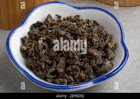 Ciotola con aromatica secca cinese Oolong se Chung tè foglie primo piano i Foto Stock