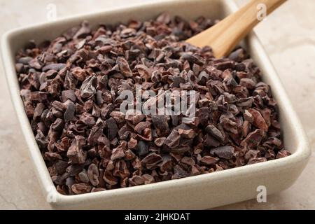 Polpette di cacao, essiccate, tritate e fermentate, in un recipiente di ceramica da vicino Foto Stock