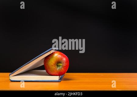 Red apple e vecchi libri sul piano portapaziente in legno Foto Stock