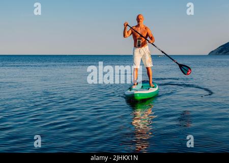 Luglio 5, 2022. Dalaman, Turchia. Uomo anziano a bordo di paddle sul mare blu. Stile di vita attivo per l'uomo anziano Foto Stock