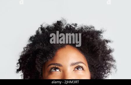 Le mie idee vengono naturalmente: Una donna che guarda mentre si alza su uno sfondo grigio. Foto Stock