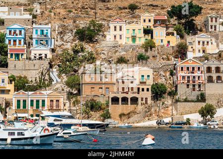 Seascape con vista panoramica delle tradizionali case colorate e la porta chiamato Yalos con le barche a vela in Symi isola Dodecaneso, Grecia. Foto Stock