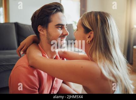 Primo piano di felice giovane coppia caucasica seduta insieme e condividere romantico momento intimo a casa. Giovane donna che mette le braccia intorno al ragazzo Foto Stock
