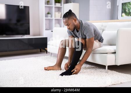 Uomo che mette su calze di compressione mediche sulle gambe Foto Stock