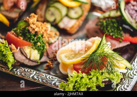 Smørrebrød tradizionale danese o sandwich all'aperto serviti in un piatto, roast beef con remoulade, pomodoro e rafano grattugiato su pane di segale danese Foto Stock