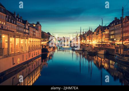 Bella vista con la facciata colorata di case tradizionali e vecchie navi di legno lungo il canale Nyhavn o New Harbour, vista notturna Foto Stock