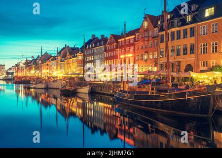 Bella vista con la facciata colorata di case tradizionali e vecchie navi di legno lungo il canale Nyhavn o New Harbour, vista notturna Foto Stock