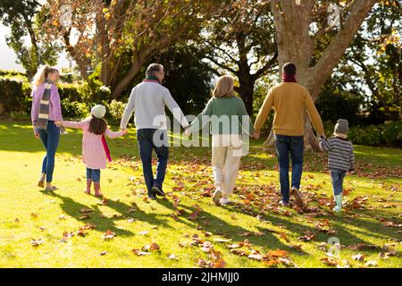 Immagine della vista posteriore della famiglia caucasica multigenerazione che trascorre il tempo nel giardino d'autunno Foto Stock