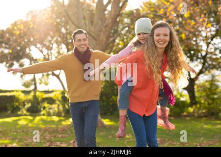 Immagine di genitori caucasici felici e figlia in autunno giardino Foto Stock