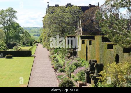 Un sentiero di ghiaia corre tra una siepe tagliata e un prato ben curato nei terreni di una casa di campagna inglese Foto Stock