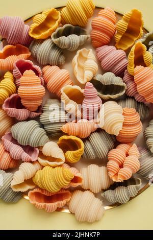 Conchiglie di Conchiglie di Conchiglioni di mare secco Pasta colorata, spinaci, barbabietole, curcuma e paprika per colorare la pasta verde, rosa, giallo, arancio Foto Stock