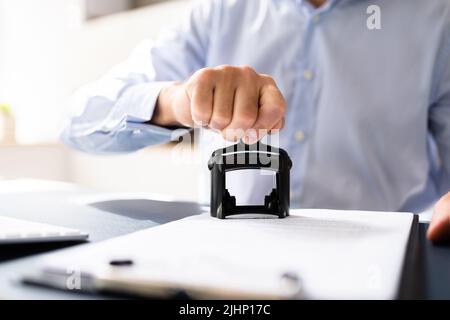 Close-up di mano di una persona Stamping approvato con timbro sul documento alla scrivania Foto Stock