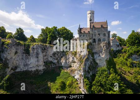 Veduta aerea del castello di lichtenstein (Schloss) sulla scogliera boschiva delle Alpi sveve in estate. Panorama stagionale del romantico palazzo da favola in stile gotico ravvivante sul cielo. Famoso punto di riferimento europeo Foto Stock