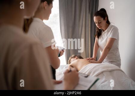 Insegnante donna che aiuta l'addestramento dello studente a diventare massaggiatrice, salute benessere massaggio di formazione concetto Foto Stock