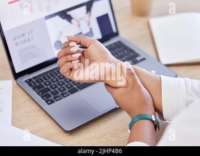 Primo piano di un uomo d'affari che tiene il polso nel dolore mentre si siede ad una scrivania al lavoro. Un professionista che tocca il braccio irritato mentre lavora Foto Stock