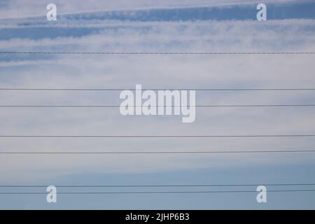 Linee di trasmissione della potenza contro il cielo blu nuvoloso con spazio di copia Foto Stock