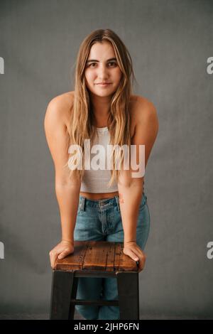Primo piano giovane donna appoggiata su uno sgabello con le mani Foto Stock