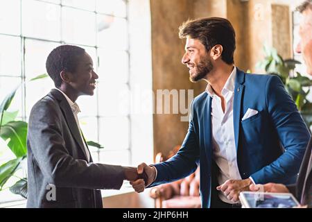 Coppia multietnica di uomini d'affari handshake in ufficio - businessperson concludere un accordo con successo - accordo multirazziale, internazionale A. Foto Stock