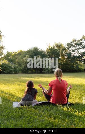 Madre di mezza età con bambino meditare insieme nel parco Foto Stock