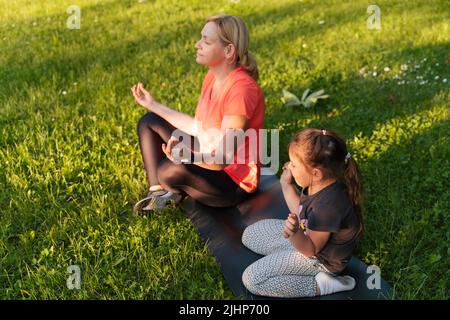 Madre di mezza età con bambino meditare insieme nel parco Foto Stock