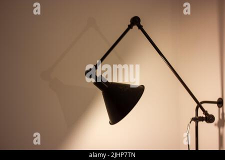 Lampada da comodino in camera oscura. L'elegante lampada per interni moderna illumina in modo piatto. Illuminazione minimalista in stile scandinavo. Design retrò classico. Foto Stock