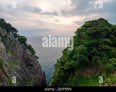 L'apertura tra le aspre scogliere costiere rivela l'alba del mattino su un mare calmo Foto Stock