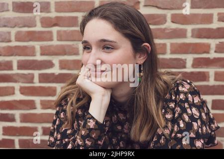 Primo piano scatto di un bel Teenager marroni sorridente, su uno sfondo rosso mattone con spazio copia. Foto di alta qualità Foto Stock