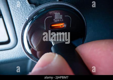 Vista ravvicinata del collegamento del cavo USB di tipo C a un potente caricatore per auto, ripresa con l'obiettivo della sonda macro Foto Stock