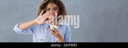 Latino americana giovane donna gettando soldi via dalla mano, mazzo di contanti Foto Stock