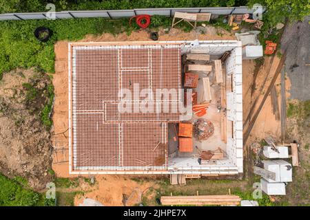 Casa di campagna in costruzione con materiali da costruzione, attrezzi e spazzatura. Direttamente sopra la vista aerea Foto Stock