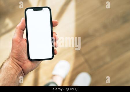 Smartphone mockup, Internet delle cose e concetto di casa intelligente, uomo che utilizza il telefono cellulare. Primo piano del dispositivo di tenuta manuale con schermo vuoto in casa interi Foto Stock