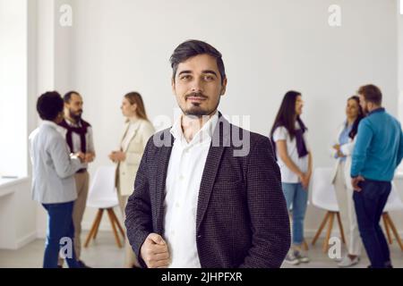 Affascinante uomo d'affari che si pone di fronte alla sua squadra multietnica su uno sfondo bianco Foto Stock