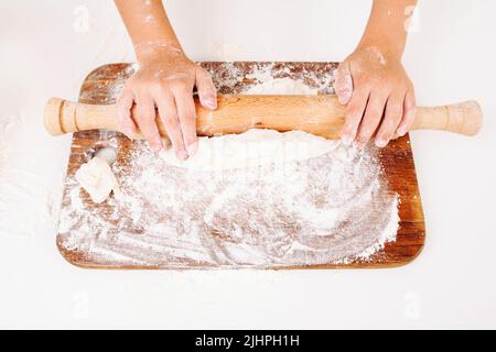 Le mani piccole si stendono l'impasto con la spilla, vista dall'alto Foto Stock