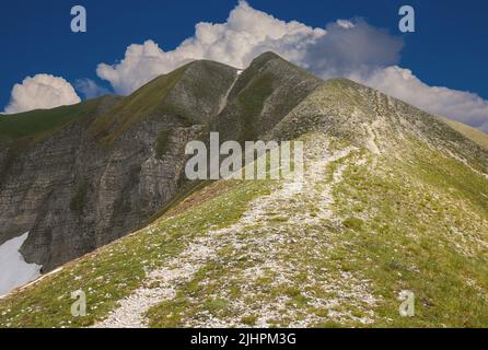 Vista panoramica dell'alta vetta del Monte Bove sud nella stagione primaverile con cielo blu e nuvole, regione Marche, Italia Foto Stock