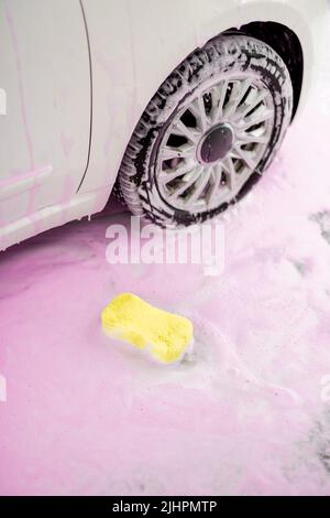 Spugna gialla in schiuma rosa al lavaggio dell'auto Foto Stock