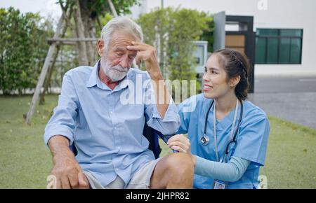 Paziente maschio depresso che piange sulla sedia a rotelle. Giovane infermiere che lo consolava. Uomo anziano infelice con malattia geriatrica o depressiva. Terapista Foto Stock