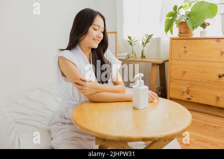 donna con bottiglia di crema di lozione della pelle sul tavolo, trattamento e cura del corpo concetto Foto Stock