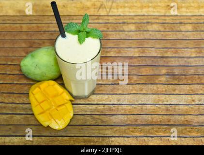 Mango lassi con mango fresco a fette su sfondo ligneo Foto Stock