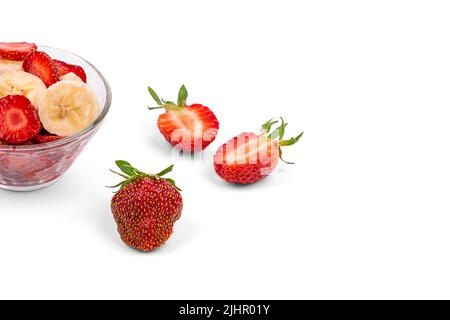 Fragole fresche, un piatto con fragole a fette e una banana, su sfondo bianco da vicino Foto Stock